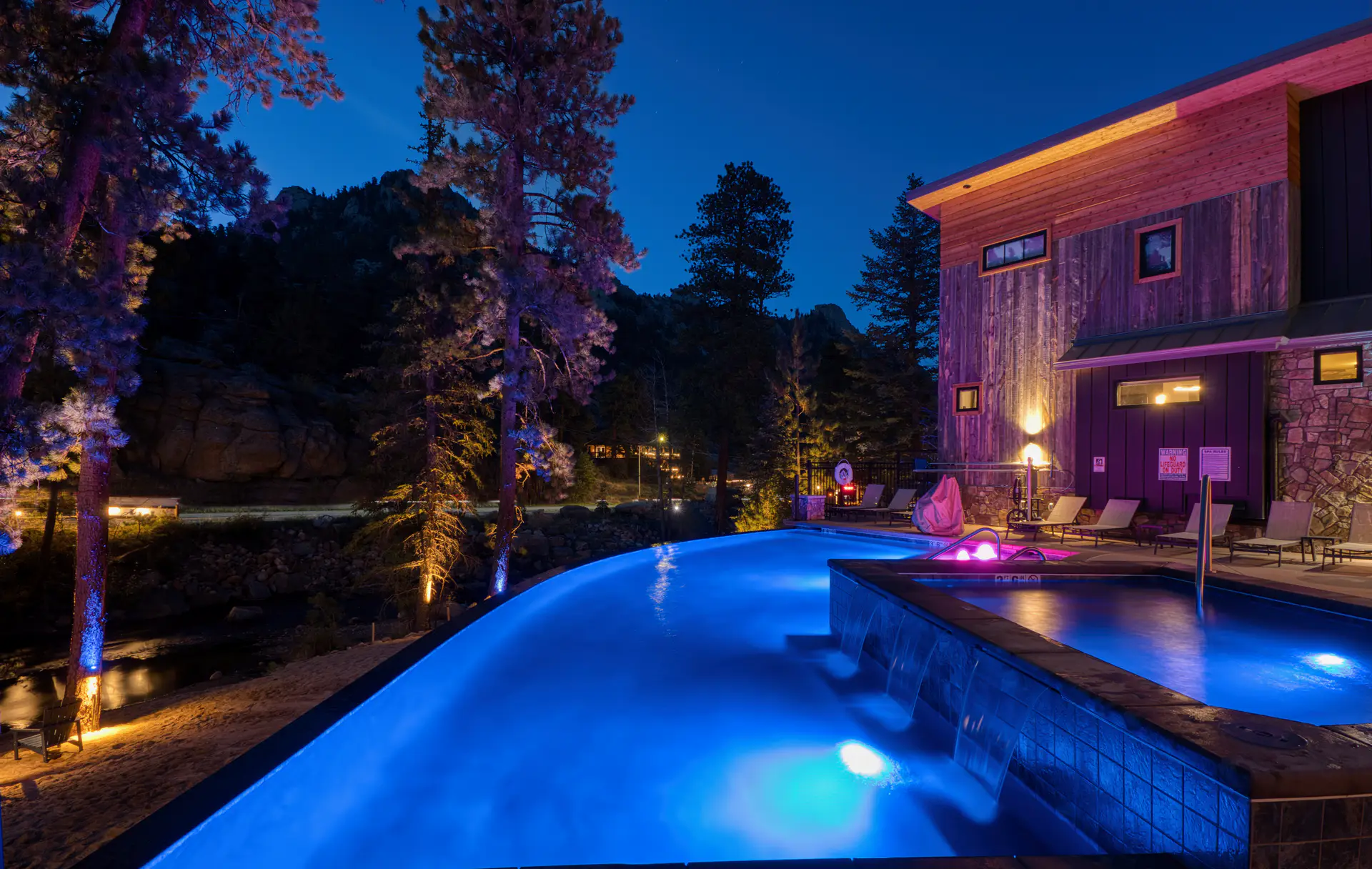 DreamView infinity pool illuminated blue at night beside Fall River